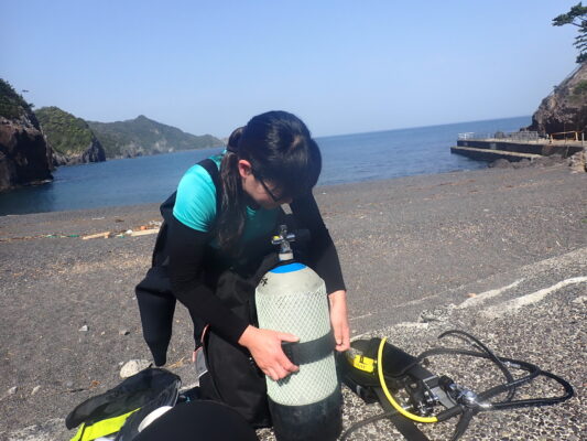 ダイビングの講習でダイビングの器材をタンクにつけている講習生